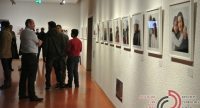Menschenmenge vor Wand mit ausgestellten Fotos in einem Ausstellungsraum, Quelle: DTF