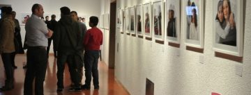 Menschenmenge vor Wand mit ausgestellten Fotos in einem Ausstellungsraum