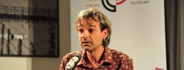 Mann in rot-weißen Hemd vor Banner des DTF