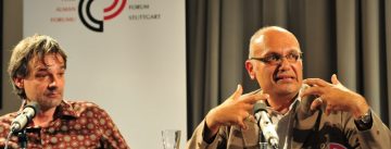 zwei Männer am Holztisch vor Banner des DTF