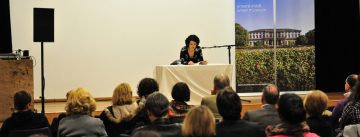 Dilek Güngör sitzt an einem weißen Tisch neben Banner des Stadtmuseums