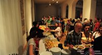 Menschen in einem Saal mit Tellern voller Essen in den Händen, Quelle: DTF