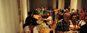 Menschen in einem Saal mit Tellern voller Essen in den Händen