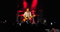 Gitarrist und Sänger allein auf rot beleuchtter Bühne vor Silhouette des Publikums, Quelle: DTF