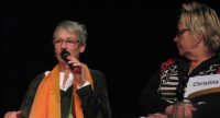 zwei Frauen sitzend auf der Bühne, die eine spricht ins Mikrofon, Quelle: DTF