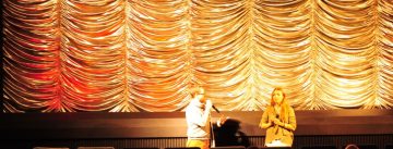 Mann und Frau vor goldenem Vorhang im Kinosaal