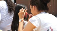 junge Frau schminkt Mädchen mit roter Farbe, Quelle: DTF