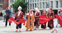 Mädchen und Jungs in traditioneller Kleidung mit roten Schildern in den Händen, Quelle: DTF