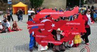 Kinder in traditioneller Kleidung stehend und hockend mit roten Schildern, welche eine Karte der Türkei darstellen, Quelle: DTF