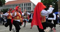 Mädchen und Jungs in traditioneller Kleidung tanzen miteinander, Quelle: DTF