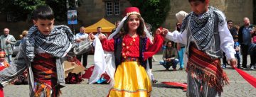 Mädchen und Jungs in traditioneller Kleidung tanzen miteinander