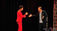 Mann im schwarzen Anzug gibt lachend die Hand einem Mann im roten Anzug, Quelle: DTF