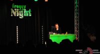 Mann sitzt am grünen Schreibtisch vor Silhouette des Publikums, Quelle: DTF