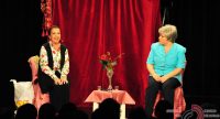zwei Frauen sitzend auf der Bühne vor Silhouette des Publikums, zwischen ihnen steht ein Blumenstrauß, Quelle: DTF