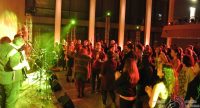 Band auf grün beleuchteter Bühne vor tanzenden Menschen, Quelle: DTF