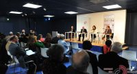 Diskussionsteilnehmer sitzend auf dem Podium vor Silhouette des Publikums, Quelle: DTF