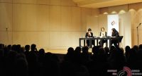 drei Frauen sitzend an Holztischen vor Banner des DTF vor Silhouette des Publikums, Quelle: DTF