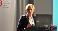 Frau in schwarzem Sakko spricht ins Mikrofon am Rednerpult vor Banner des DTF, Quelle: DTF