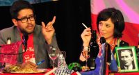 Mann und Frau sitzend am bunten Tisch voller Länderflaggen, die Frau raucht, Quelle: DTF