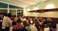 Menschen in Restaurant sitzend an Tischen, Kellner stehen zwischendrin, Quelle: DTF