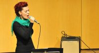 rothaarige Sängerin mit grünem Schal singend vor der Bühne, Quelle: DTF