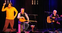 zwei sitzende und ein stehender Mann auf der Bühne mit Mikrofone und Musikinstrumente, Quelle: DTF