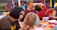Kinder und Erwachsene schminken einander an einem Tisch, Quelle: DTF