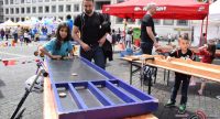 Kinder und Erwachsene rund um einen Holztisch mit Hockey-ähnlichem Spiel, Quelle: DTF