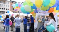 Frauen in blauen SHirts halten Haufen von bunten Ballons in den Händen, Quelle: DTF
