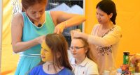 Junge Frauen in einem gelben Zelt flechten das Haar anderer junger Frauen, Quelle: DTF