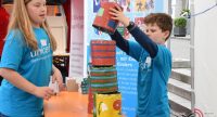 Junge und Mädchen in blauen Shirts der unicef stapeln Farbeimer aufeinander, Quelle: DTF