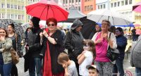 Menshen und Kinder mit bunten Regenschirmen auf dem Platz, Quelle: DTF