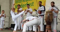 Kinder und Erwachsene in weißer Kleidung zeigen barfuß eine Capoeira Vorführung, Quelle: DTF