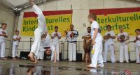 Kinder und Erwachsene in weißer Kleidung zeigen barfuß eine Capoeira Vorführung, Quelle: DTF