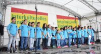Kinderchor in blauen Shirts auf der Bühne vor Banner des Kinderfestes, Quelle: DTF