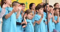 Kinderchor in blauen Shirts auf der Bühne vor Banner des Kinderfestes, Quelle: DTF