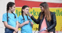 zwei Mädchen in blauen Shirts sprechen mit junger Frau in Lederjacke, Quelle: DTF