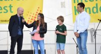 vier Menschen auf der Bühne vor Bannern des Kinderfestes, Quelle: DTF