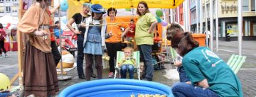 Kinder und Erwachsene rund um ein blaues Aufblasvecken fischen nach Gummienten darin