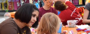 Kinder und Erwachsene schminken einander an einem Tisch