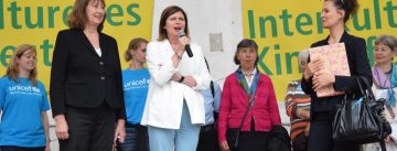 Frauengruppe sprechend auf der Bühne mit Banner des Kinderfestes im Hintergrund