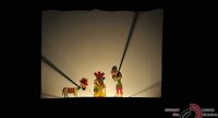Schattentheater einer traditionell angezogenen Figur und einer Tiergestalt neben einem bunten Baum, Quelle: DTF