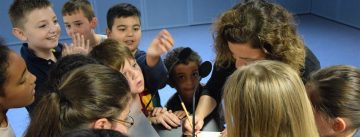 Frau inmitten von Kindern gibt Autogramme