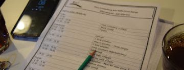 Blätterstapel neben einem Handy mit laufendem Timer, rechts ein Glas mit Cola-artiger Flüssigkeit