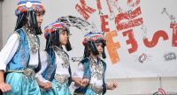 Mädchen in traditioneller Kleidung tanzend vor Banner des Kinderfests, Quelle: DTF