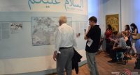 Menschen stehend vor einer Wand mit blauen arabischen Schriftzeichen, Quelle: DTF