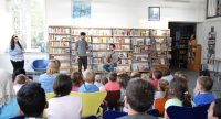 zwei junge Männer und ein Mädchen vor sitzendem Publikum, Quelle: DTF