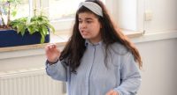 Mädchen in blauem Hemd spricht gestikulierend, Quelle: DTF