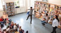 zwei junge Männer und ein Mädchen vor sitzendem Publikum, Quelle: DTF