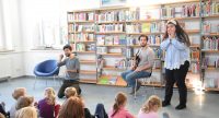zwei junge Männer und ein Mädchen vor sitzendem Publikum, Quelle: DTF